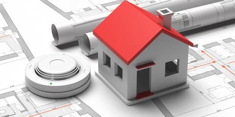 smoke-detector-and-small-house-on-blueprint-drawin-2022-12-16-12-23-56-utc